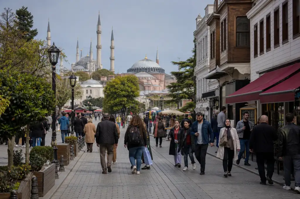 Street-level view of Istanbul's Sultanahmet district with historic buildings, pedestrians, Hagia Sophia and the Blue Mosque in the background